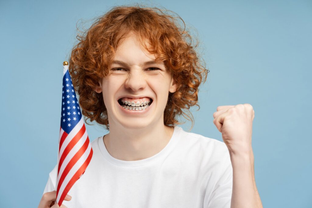 Red-haired boy with braces holding the American flag